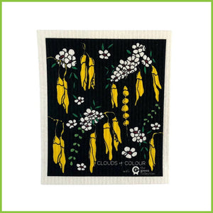 A Spruce Swedish dish cloth with the Kowhai design by Clouds of Colour. The dish cloth is black with yellow kowhai and white manuka flowers all over it.