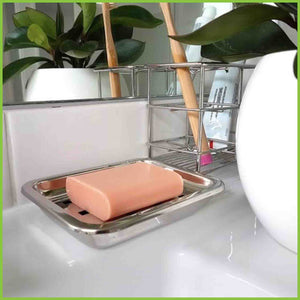 A stainless steel soap tray being used in a bathroom to store hand soap.