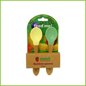 A pack of 2 soft silicone baby spoons. These feeding spoons are from the brand 'Munch', have bamboo handles and silicone tips in two different colours, green and yellow. The spoons are packaged in a simple cardboard holder.