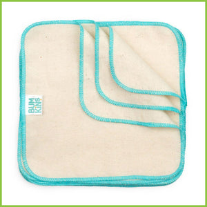 A pile of Bumkins reusable baby cloth wipes. Three of the wipes have been folded over at the top right corner. The wipes are about 21 x 21cm in size and are a natural unbleached cotton colour. There is also an aqua blue stitched hem all the way around each wipe. This image is take look straight down on the wipes.