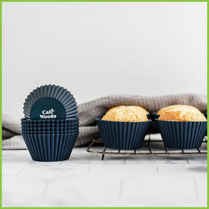 A stack of reusable silicone muffin liners next to a rack of freshly baked cupcakes.