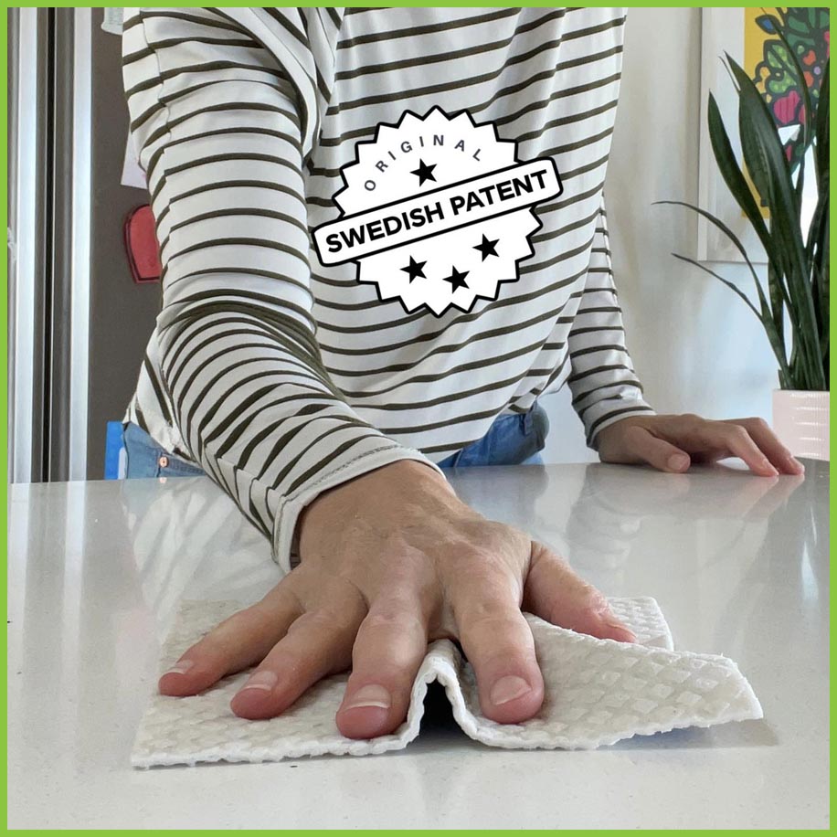 A Spruce dish cloth being used to wipe down a kitchen bench top. A stamp reads: 'Original Swedish Patent.'