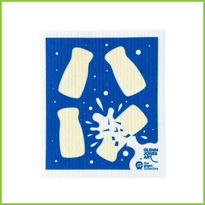A Spruce Swedish dish cloth with the milk bottles design by Glenn Jones. The cloth is a bright royal blue with four lolly milk bottles. One of the bottles has burst open and has white milk splashing out over the cover of the dish cloth.