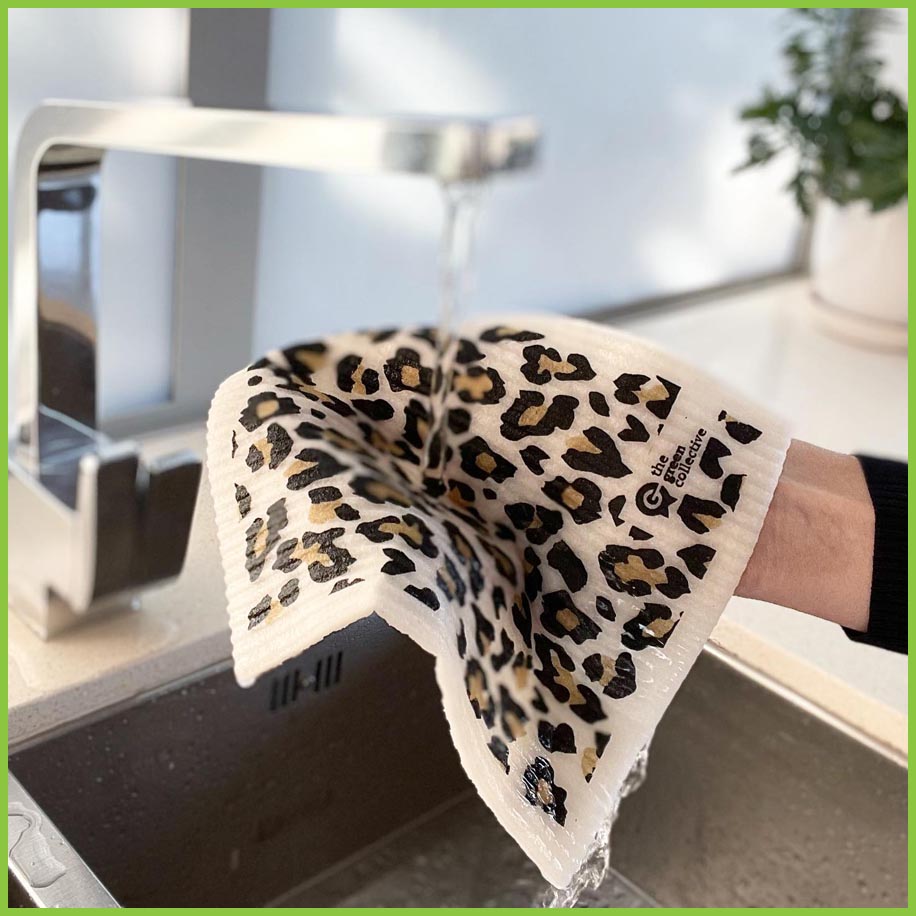 A spruce dish cloth being held underneath a running tap. This image gives a good indication of the size and texture of the dish cloth.