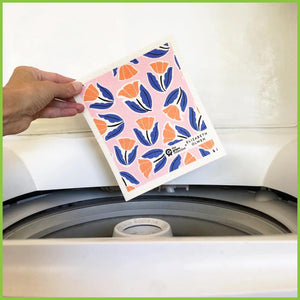 A Spruce Swedish dish cloth being held over a washing machine to demonstrate that they can be washed that way.