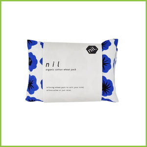 A folded up wheat bag wrapped in a white packaging label. Label reads 'Nil organic cotton wheat pack. Relieving wheat pack to calm your mind, relieve aches or just relax.' This wheat bag has a bold blue flower print.