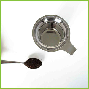 Stainless steel tea infuser with a teaspoon of loose tea leaves.