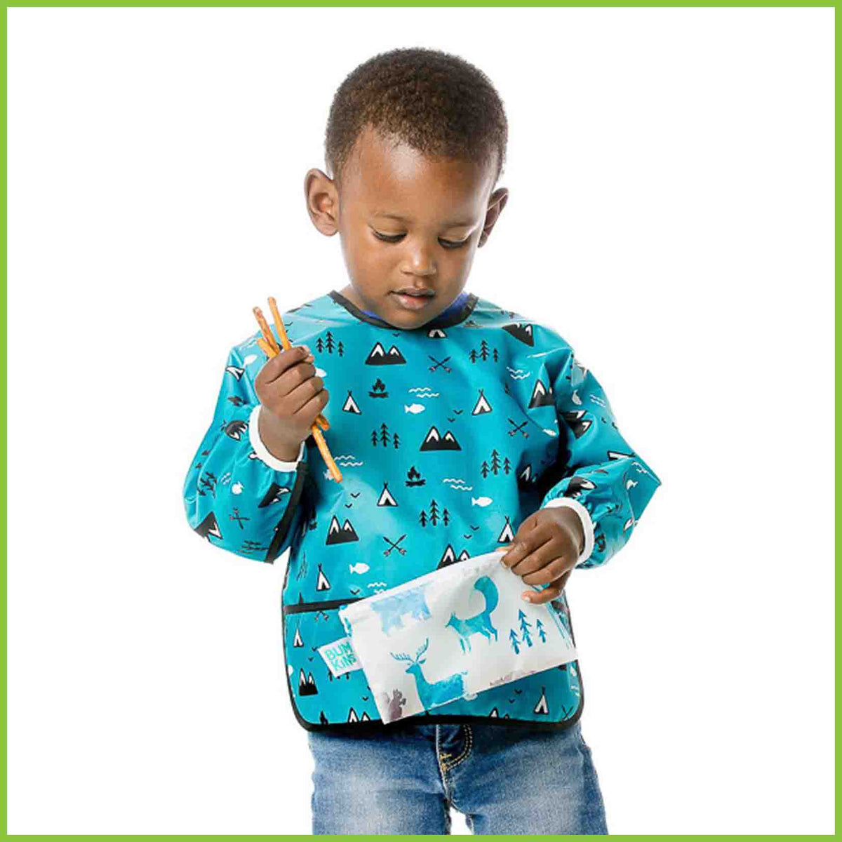 A little boy eating snacks from a Bumkins snack bag.