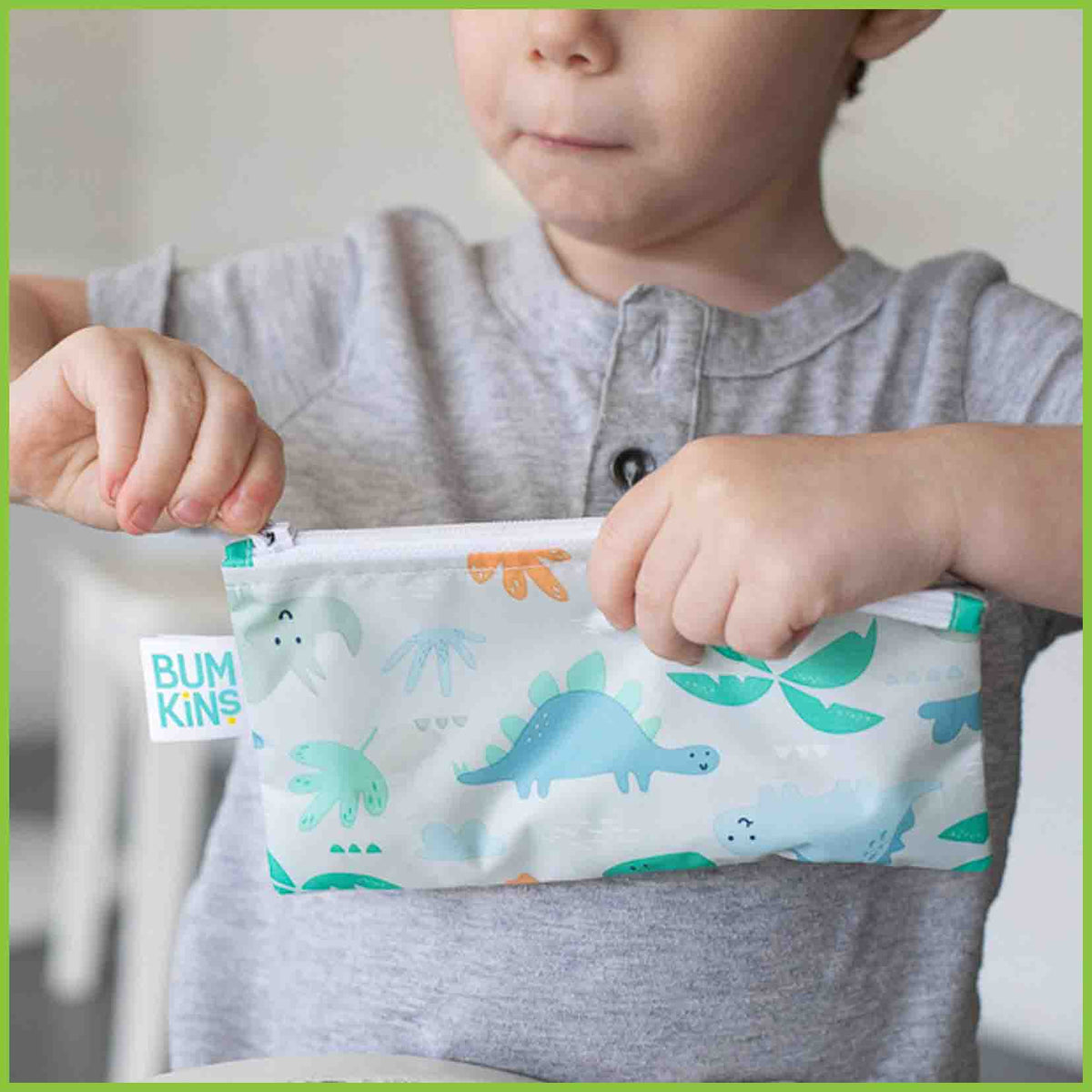A young boy zipping closed a Bumkins snack bag.