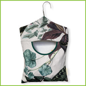 A cotton peg bag with a stainless steel hanger for easy hanging. The peg bag has a nature inspired botanical leaf print.