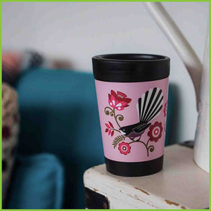 A reusable cup by CuppaCoffeeCup with the Pink Fantail design sitting on a table.