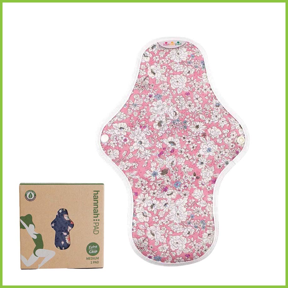 A reusable sanitary pad from Hannah. The image shows a single pad on a white background with its box beside it. The cotton pad is showing you its patterned side. The pattern is a pretty pink floral pattern known as 'Antique Pink'.