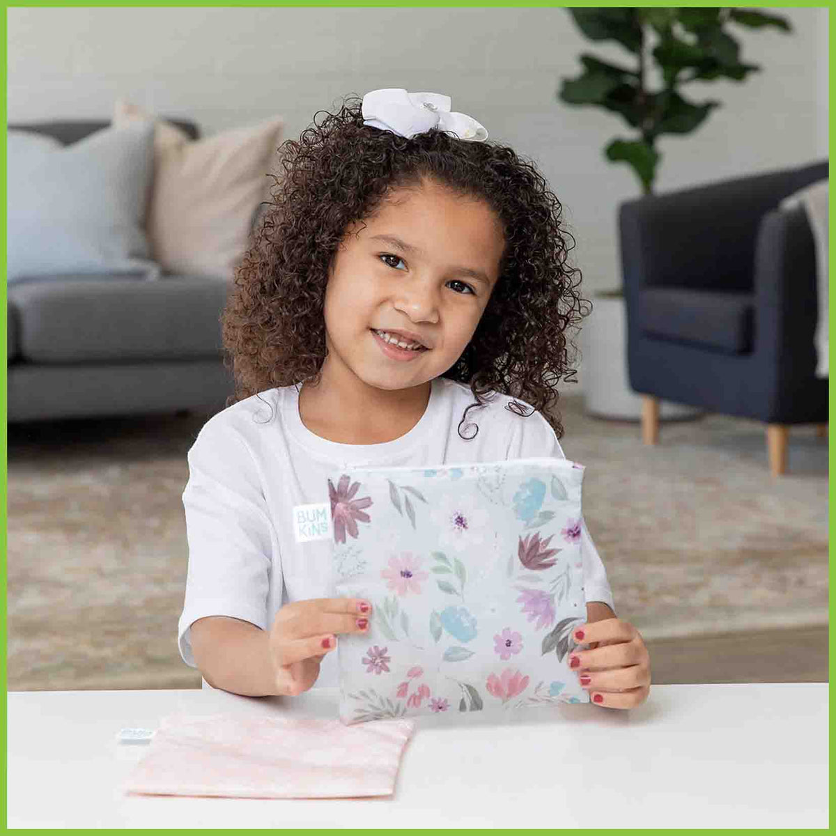 Two Bumkins large snack/sandwich bags in the Floral and Lace designs, with one bag being held up by a young girl.