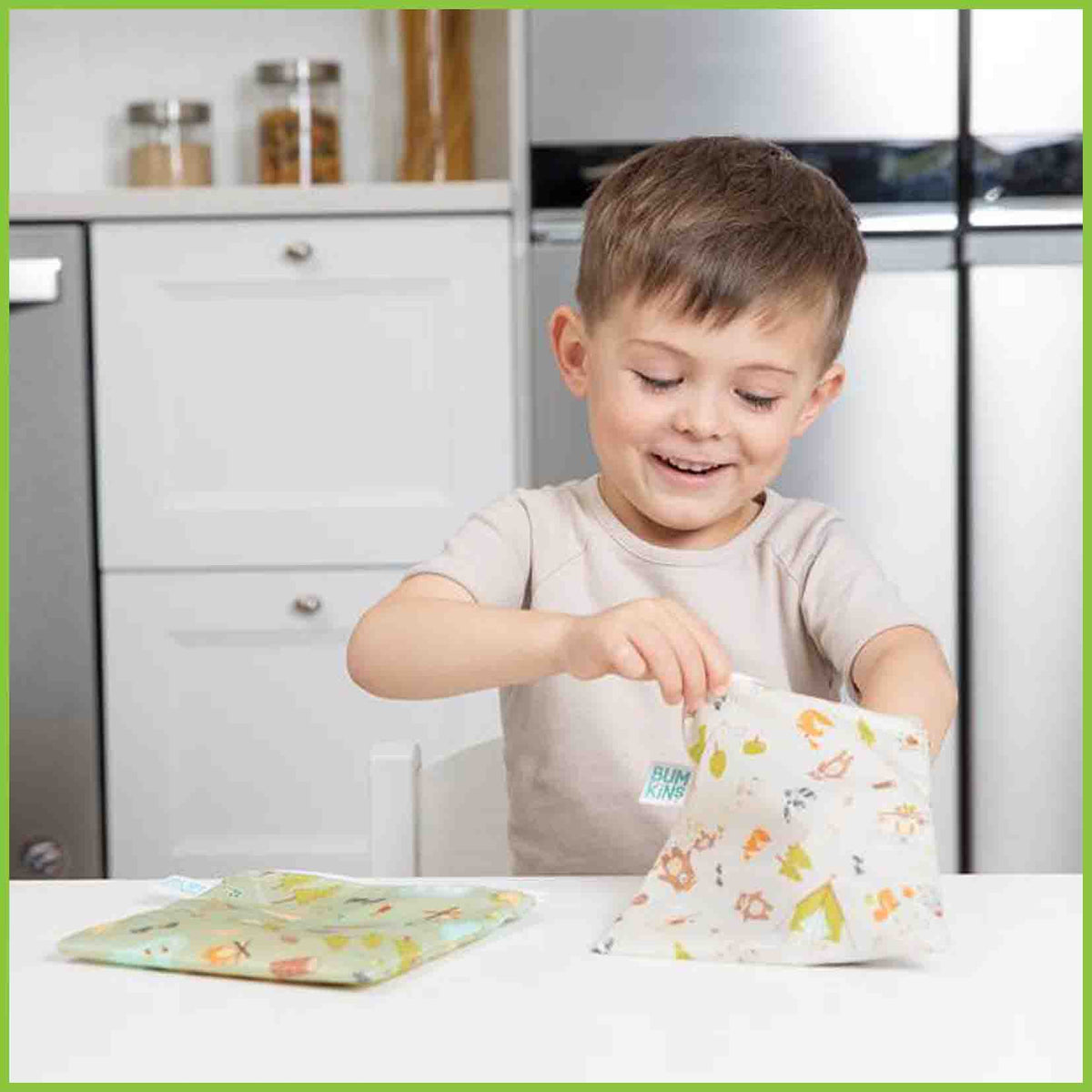 Two Bumkins large snack/sandwich bags in the camping gear designs, with one bag being reached into by a young kid.