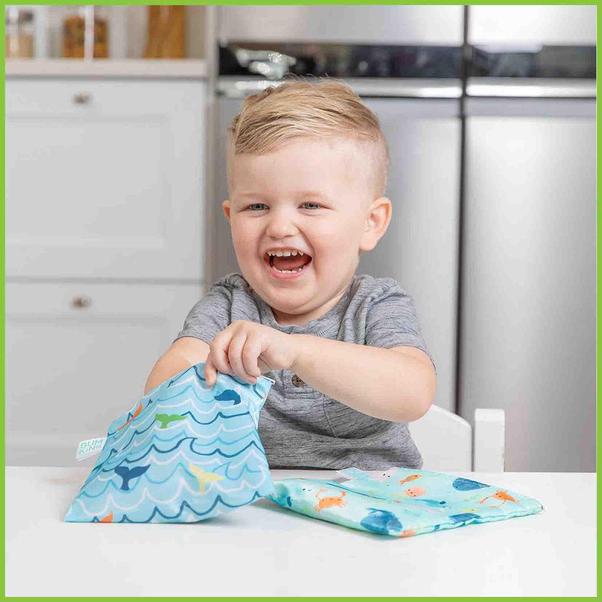Two Bumkins large snack/sandwich bags in the ocean animals designs, with one bag being reached into by a young boy.