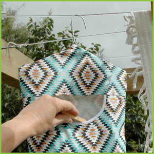 A cotton peg bag with an aztec pattern hanging on a washing line.