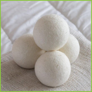 Four wool dryer balls stacked to form a pyramid. All sitting on a blanket.