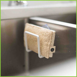 An Eco Scrub from the Good Change Store NZ sitting at the side of a kitchen sink. An eco scrub is a kitchen cleaning sponge with an abrasive natural scrubber sewn onto one side.