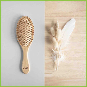 Bamboo and natural rubber hair brush, looking down on it as it's lay on a table.