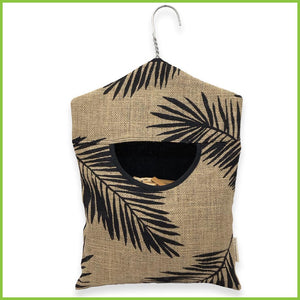 A peg bag made from jute with a cotton lining. It also has a stainless steel hanger to hang onto your washing line. The peg bag has a bold black palm leaf pattern.