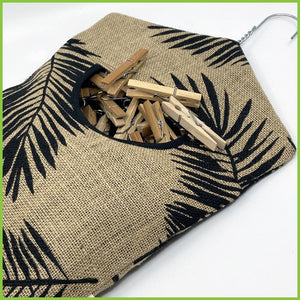 A palm leaf peg bag lying on a white surface with lots of pegs being stored in it.
