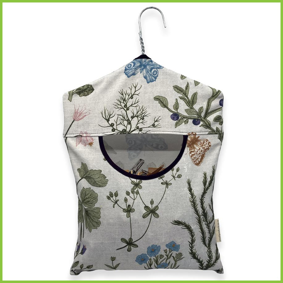 A cotton peg bag with a stainless steel hanger. The peg bag has a wild garden print.