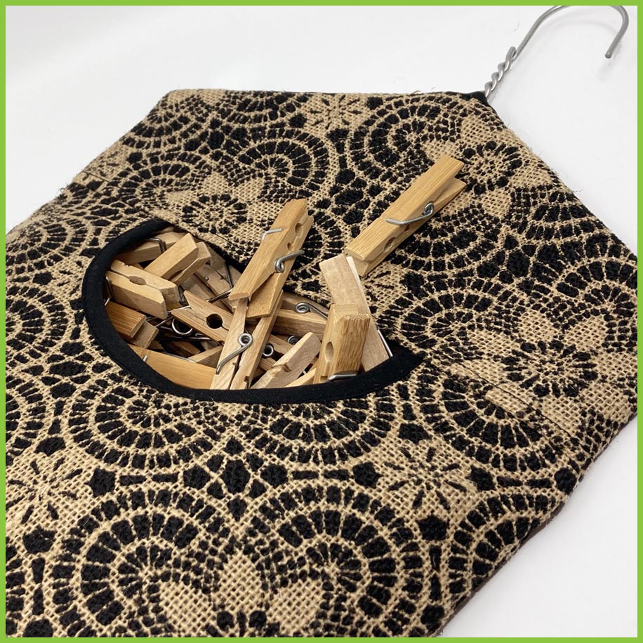 the geo floral peg bag lying on a white surface. Lots of pegs are being stored in the bag. 