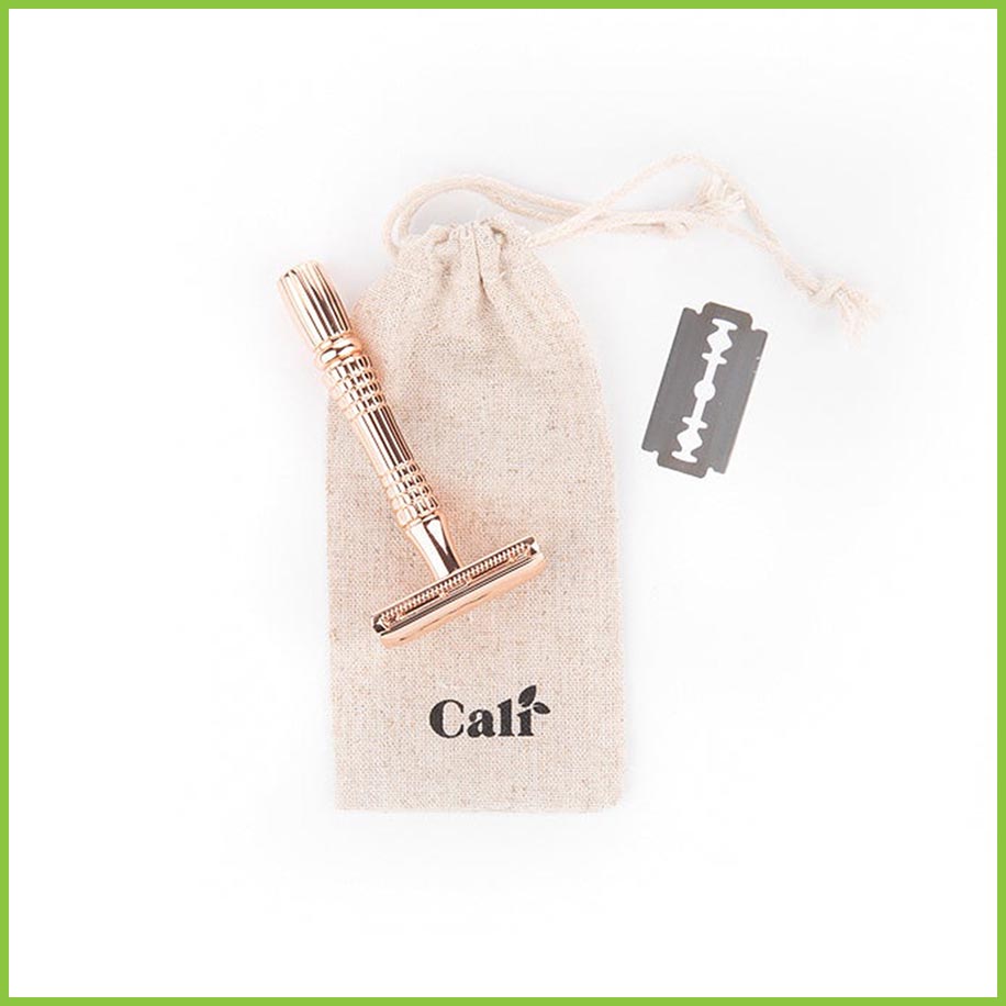 A linen travel bag for a safety razor, lying on a white surface with a copper razor and a blade lying on top.