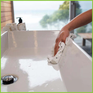 A reusable bamboo towel is being used to clean a bathroom sink.