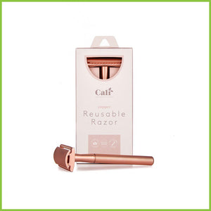 A copper safety razor in its box with another lying in front of it.