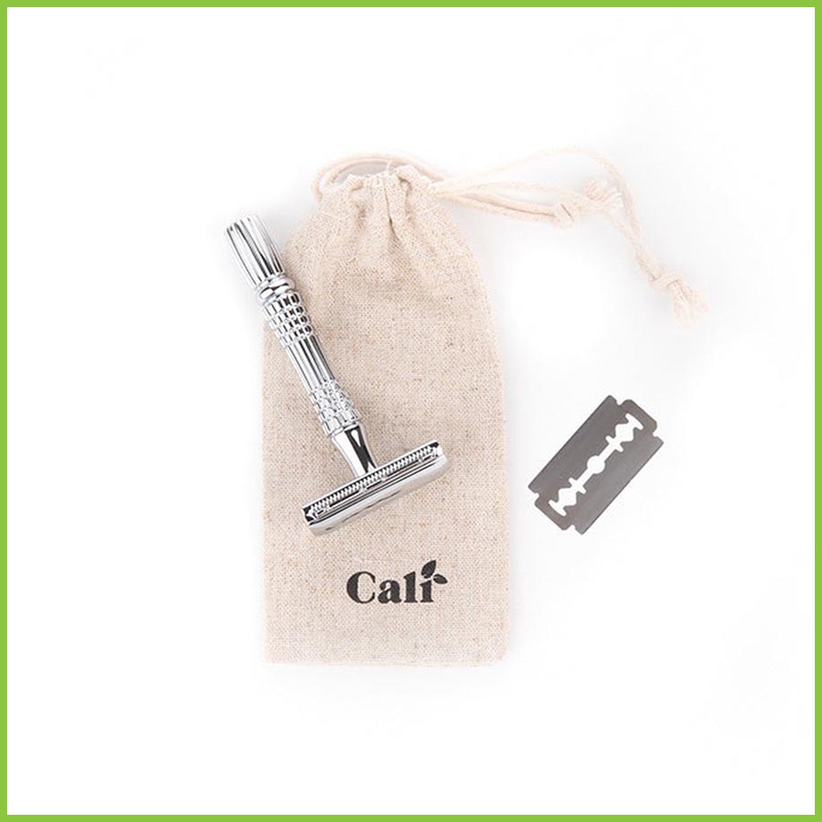 A linen travel bag for a safety razor lying in a white surface,  with a razor and blade lying on top of it.