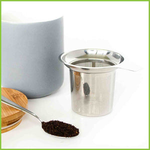 Stainless steel tea infuser with a teaspoon of loose tea leaves.